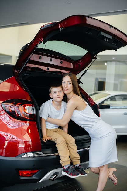 Mamá feliz abraza a su hijo después de comprar un auto nuevo en un concesionario de autos