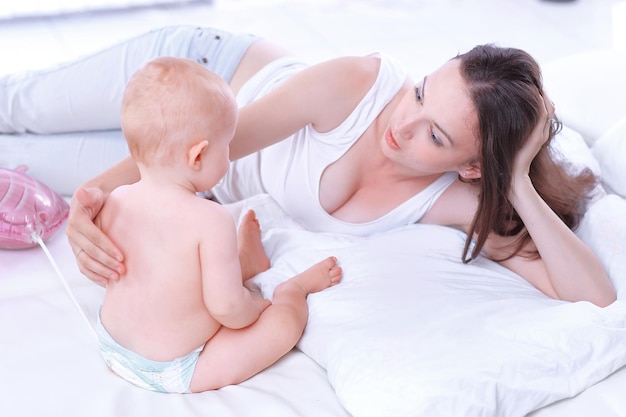 Mamá feliz hablando con el bebé acostado en la cama