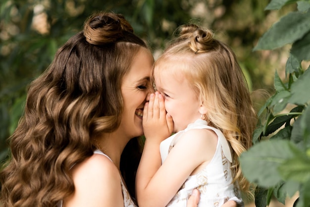 Mamá feliz juega con su hija afuera con vestidos a juego en un día soleado