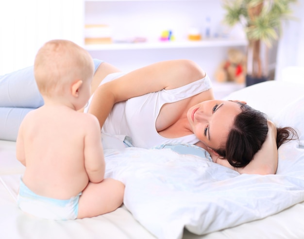 Mamá feliz jugando con su bebé en el sofá. el concepto de maternidad.