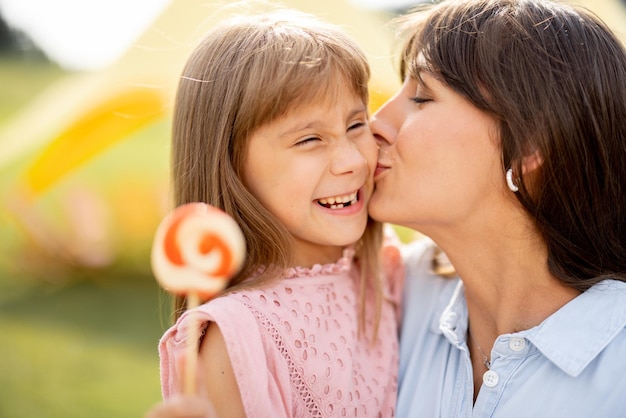 Mamá feliz con una niña visita un parque de diversiones