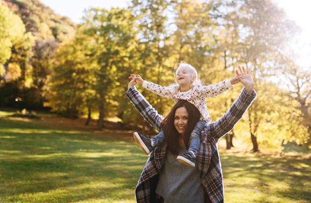 Mamá feliz con su pequeña hija en el parque de otoño recreación al aire libre Mamá e hija