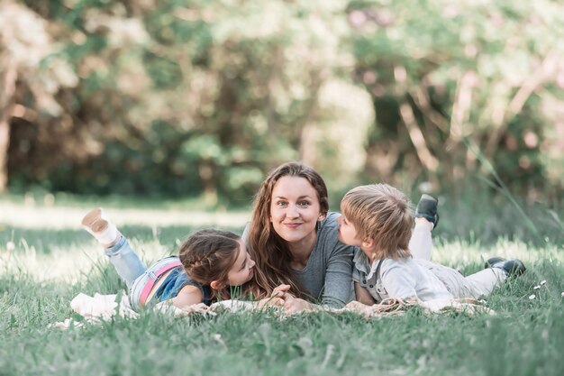 Mamá feliz con sus bebés en el césped en un día de verano