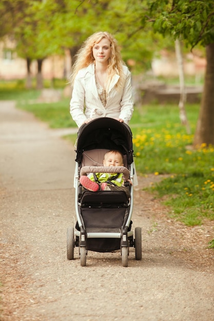 Mama geht mit dem Kind im Kinderwagen spazieren