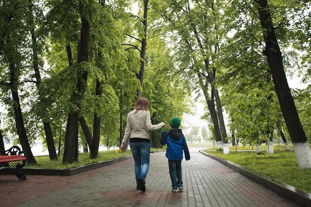 Mama geht mit ihrem Sohn im Sommer spazieren, geht mit Familie, Familientraditionen, Liebe und Verständnis