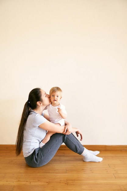 Mama hält das Baby auf ihrem Schoß und küsst sie