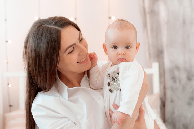 Mama hält das Baby zu Hause in den Schlafzimmerküssen