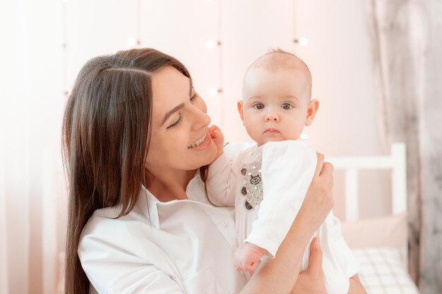 Mama hält das Baby zu Hause in den Schlafzimmerküssen