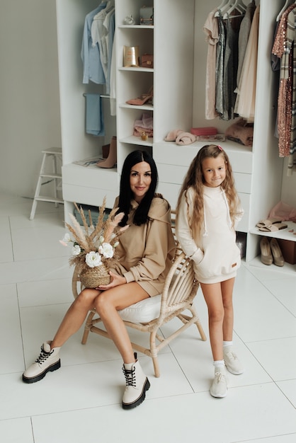 Mamá hermosa y elegante con las piernas desnudas e hija en el estudio