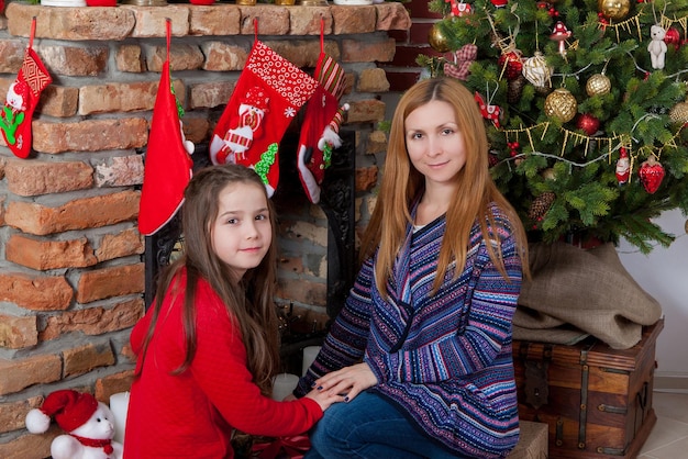 Mamá con hija cerca del árbol de Navidad