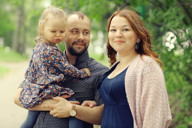 Mamá, hija pequeña y papá, una familia joven en un paseo por el parque en verano