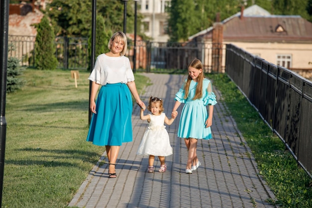 Mamá con hijas camina en el parque en verano. paseo familiar