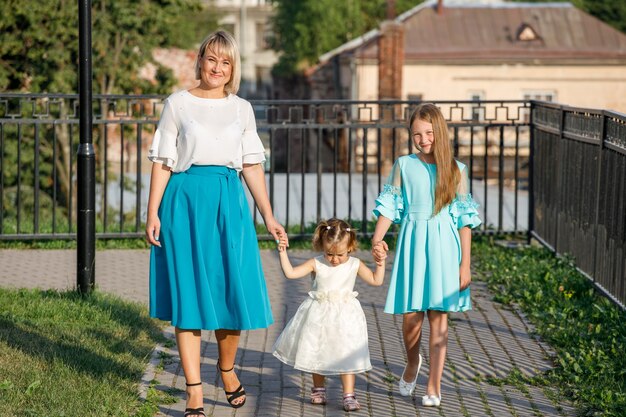 Mamá con hijas camina en el parque en verano. paseo familiar