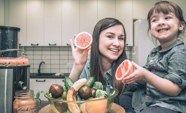 Mamá con hijos en la cocina prepara jugo fresco