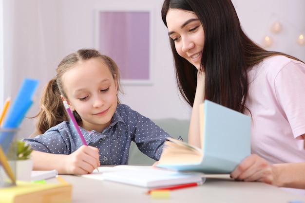 Mama hilft dem Mädchen bei den Hausaufgaben Kinder und Eltern