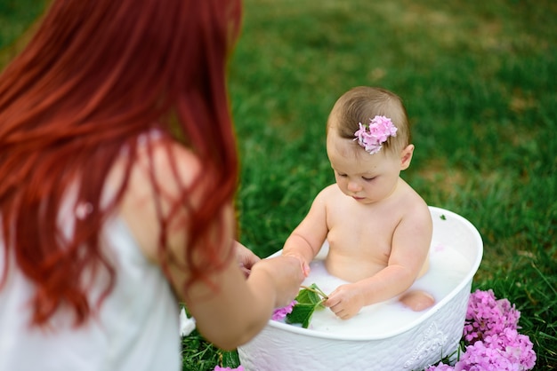 Mama hilft ihrer kleinen einjährigen Tochter beim Baden im Badezimmer.