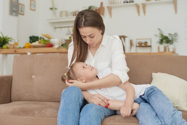 Mama hört auf die Probleme ihrer kleinen Töchter, umarmt sie und tröstet sie