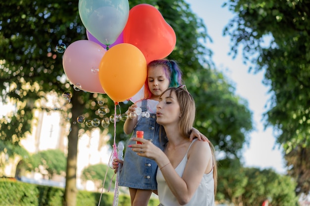 Mamá joven con hija soplando pompas de jabón. Imagen con enfoque selectivo