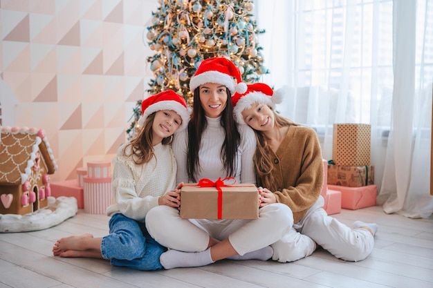 Mamá joven con niños sosteniendo regalos de Navidad