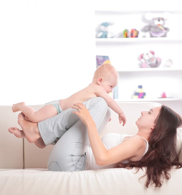 mamá jugando con un lindo bebé en el sofá de la sala de estar