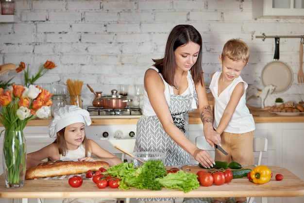 Mama kocht das Mittagessen mit den Kindern. Eine Frau bringt ihrer Tochter bei, von ihrem Sohn zu kochen. Vegetarismus und gesunde natürliche Ernährung