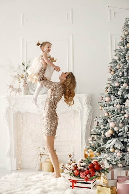 Mamá lanzando al aire a su hija cerca del árbol de Navidad