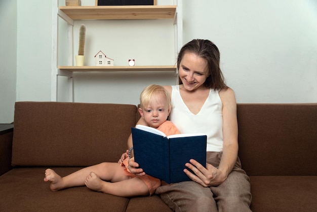 Mama liest ihrer kleinen Tochter, die auf der Couch sitzt, ein Buch vor Zeit mit ihren Lieben