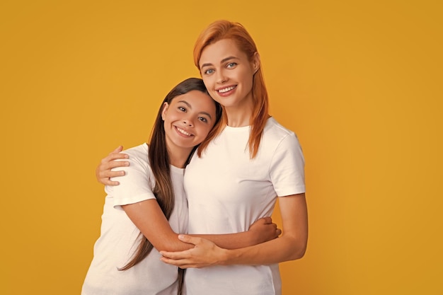 Mamá mamá y niño hija en camiseta abrazo cudding aislado sobre fondo de color amarillo estudio día de la madre amor familia