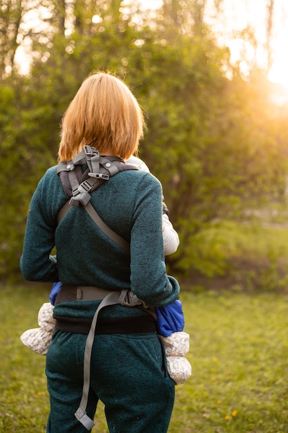 Mamá con máscara médica e hijo pequeño en un paseo por la naturaleza en el parque de primavera El niño y la madre se divierten en la actividad de fin de semana en los florecientes jardines de Sakura