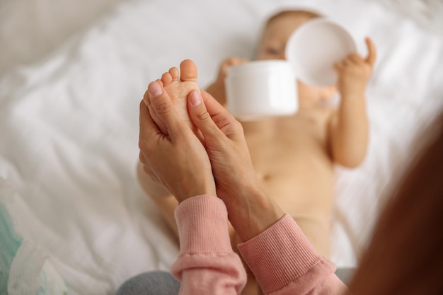 Mama massiert Babyfuß und benutzt Creme