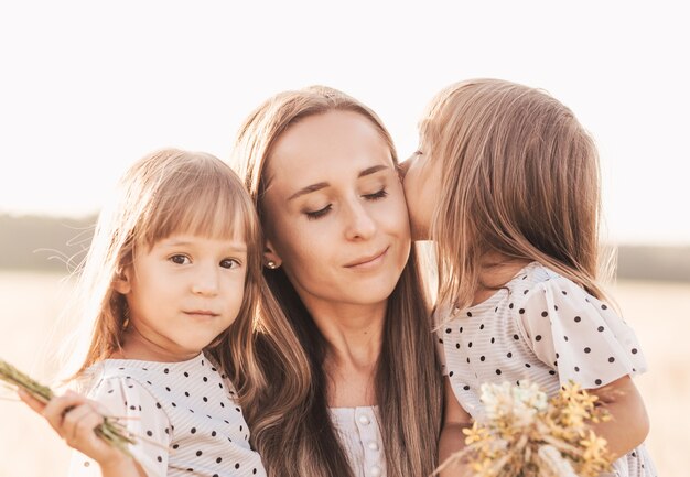 Mama mit zwei Zwillingsmädchen, die im Sommer in der Natur spielen