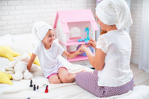 Mamá le muestra a su hija cómo hacer una manicura.