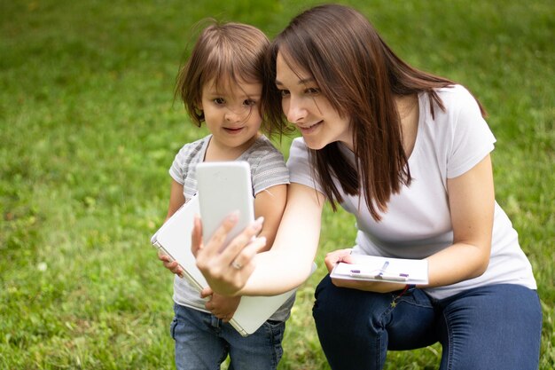 mamá le muestra el teléfono en la calle a su hija menor