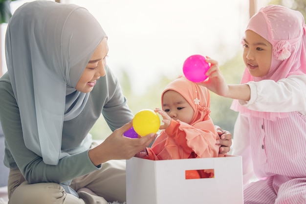 Mamá musulmana con hijab es su pequeña hija sentada en la sala de estar, Relación amorosa