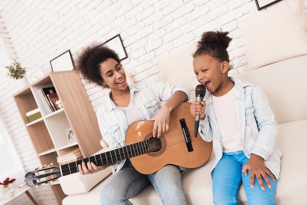 Mamá y niña cantan juntas y tocan la guitarra.