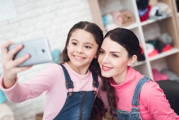 Mamá con una niña hacer selfie en un teléfono inteligente.