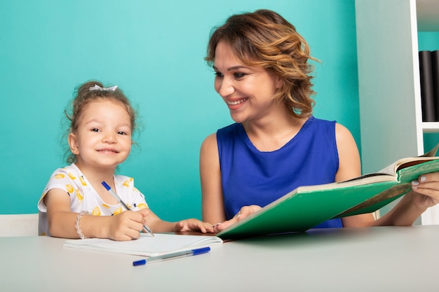 Mamá con niña juntos en casa sentados a la mesa