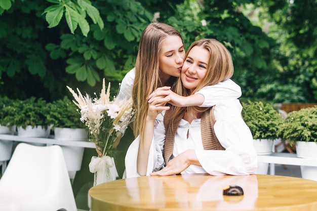 Mamá y niña sonriendo y abrazándose en el café