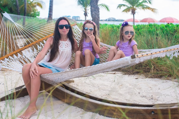 Mamá y niñas relajantes en hamaca en el resort tropical