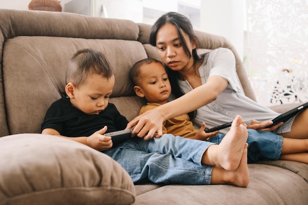 Mamá niñera y lindo hijo pequeño divirtiéndose aprendiendo usando aplicaciones móviles de teléfonos inteligentes