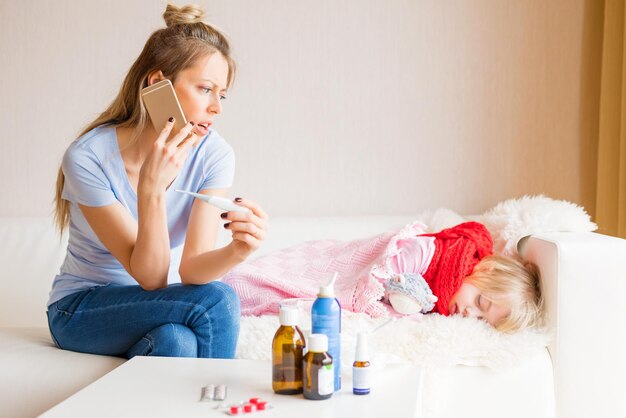 Mamá de niño enfermo llamando al médico por teléfono