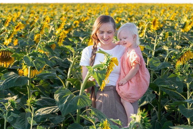 La mamá y el niño están caminando en el campo de girasoles.