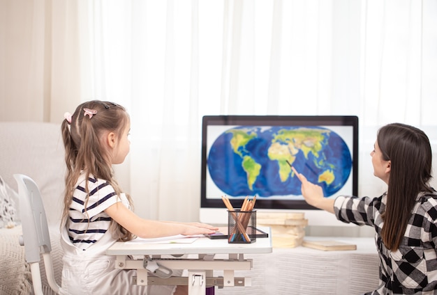 Mamá y niño hacen la tarea con geografía usando un mapa. Educación y educación en el hogar