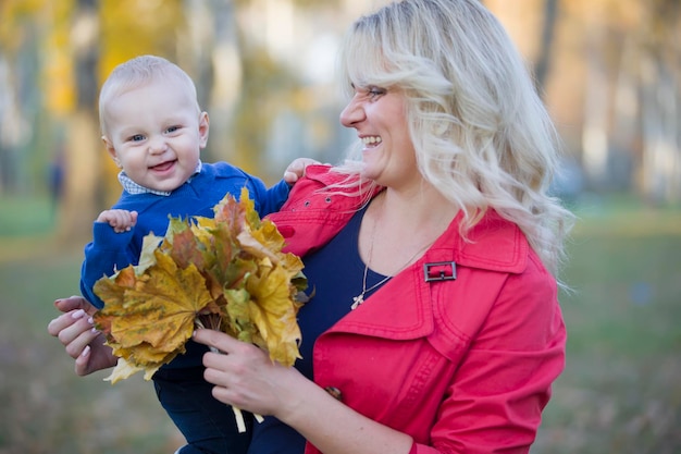 Mamá con un niño pequeño en un paseo por el parque de otoño