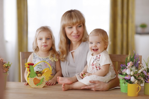 Mamá y niños con coloridos huevos de pascua en la mesa