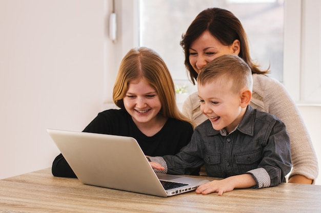 Mamá y niños mirando dibujos animados en la computadora portátil en casa