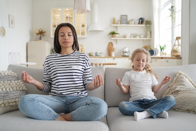 Mamá o niñera e hija adoptiva practicando yoga juntos en casa Estilo de vida saludable