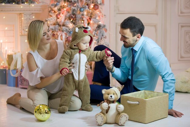 Mamá papá y bebé en el árbol de Año Nuevo Bebé con padres en Navidad