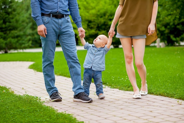 Mamá y papá caminan con el bebé en el parque.