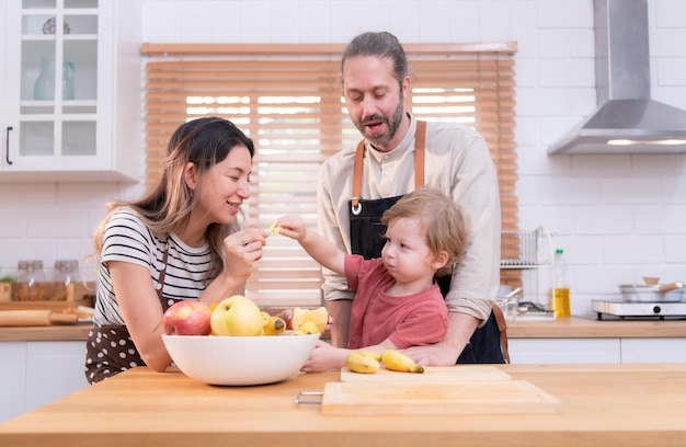 Mamá y papá en la cocina de la casa con sus hijos pequeños se divierten haciendo la cena